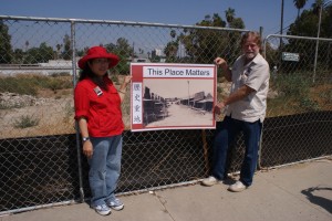 Image of Judy Lee with SOCC supporter with a sign at the Riverside, Calif. Chinatown historic site. 2009