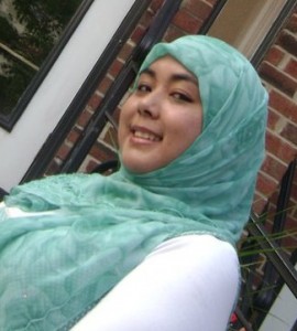 Image of Ariana Hussain, wearing a green headscarf and a white long-sleeved shirt.