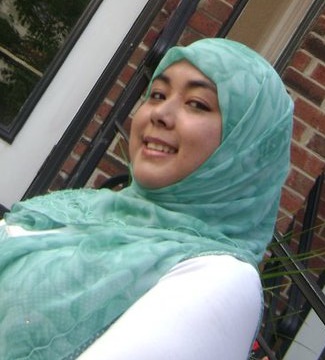 Image of Ariana Hussain, wearing a green headscarf and a white long-sleeved shirt.